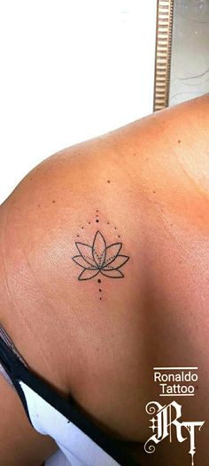 a woman's back with a small tattoo on her left shoulder and a flower in the middle