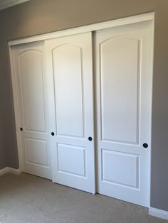 an empty room with two white doors and carpeted flooring in the middle of it