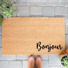 a door mat with the word bonjou written on it next to potted plants