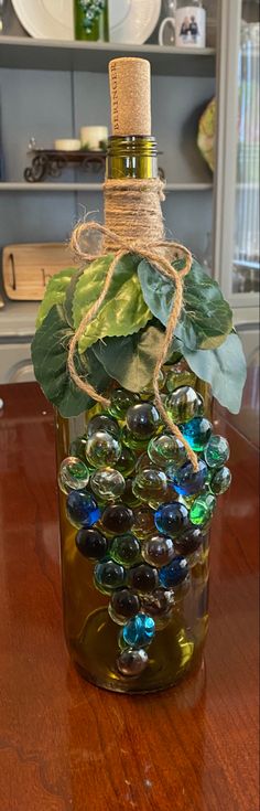 a glass bottle filled with lots of different colored stones and leaves on top of a wooden table