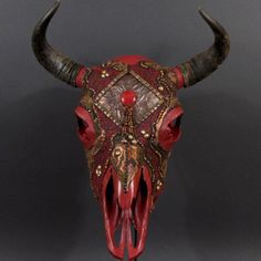 a bull's head with red and gold decorations on it, against a gray background