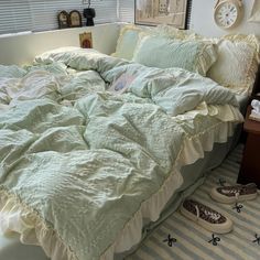 an unmade bed in a bedroom with shoes on the floor