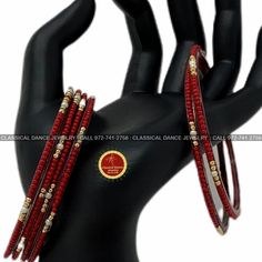 the red and gold bracelets are set on top of a black mannequin