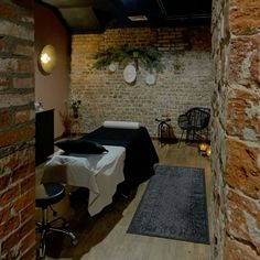 a room with brick walls and wooden floors, two beds are set up in the corner