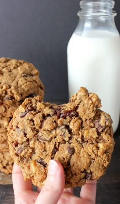 two cookies are being held in front of a glass of milk