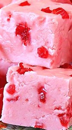 two pieces of pink fudge cake on a plate with strawberries and cherries