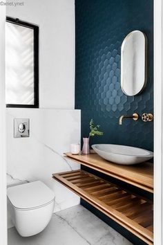 a white toilet sitting next to a wooden counter top under a bathroom mirror above a sink