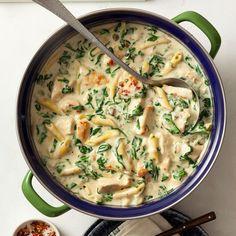 a blue pot filled with pasta and spinach on top of a white countertop