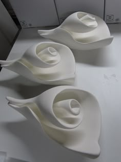 three white bowls sitting on top of a counter next to each other in the shape of swirls