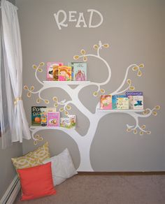 a child's room with bookshelves and a tree painted on the wall