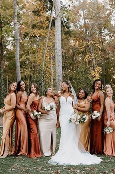 a group of women standing next to each other in front of trees and leaves on the ground