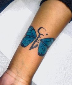 a person with a butterfly tattoo on their left arm and the other hand is holding an object