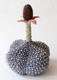 a ceramic sculpture of a flower on top of a ball with spikes in the middle