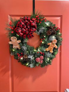 a christmas wreath on the front door decorated with gingerbreads, pine cones and red berries