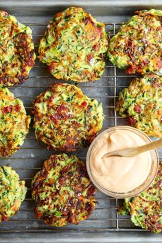 zucchini fritters on a cooling rack with a jar of dip