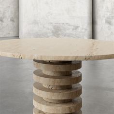 a round table made out of marble stacked on top of each other in an empty room