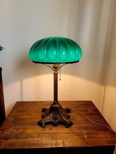 a green lamp sitting on top of a wooden table