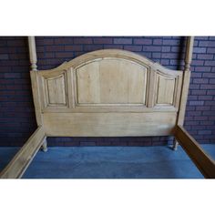 a wooden bed frame with no headboard and foot board on the bottom side, against a brick wall