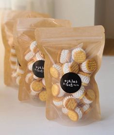 three bags filled with small cookies sitting on top of a white countertop next to each other