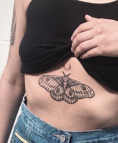 a woman's stomach with a moth tattoo on her left side ribcage