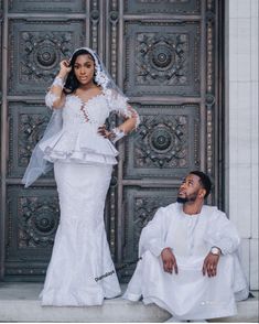 a man sitting next to a woman in front of a door wearing a wedding dress