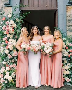 the bride and her bridesmaids pose for a photo in front of an archway with flowers