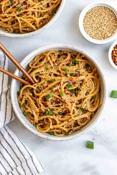 two bowls filled with noodles and topped with sesame seeds