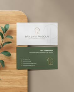 two business cards sitting on top of a wooden cutting board next to a potted plant