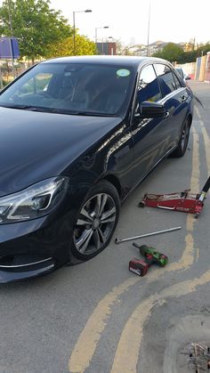 a car is parked on the side of the road with tools in front of it