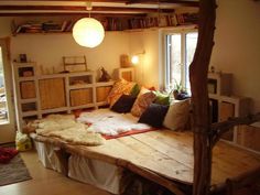 a bed made out of wooden planks in a room with windows and bookshelves