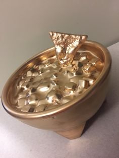 a gold plate with a triangle shaped object in it's center on a white surface