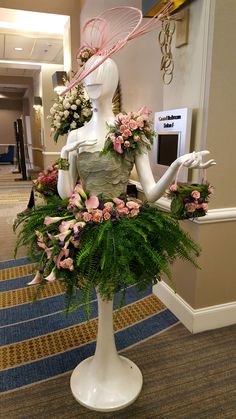 a mannequin is adorned with flowers and greenery in the lobby at a hotel