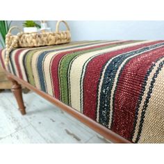 a bench with a striped blanket on it and a basket sitting on top of it