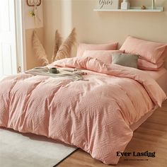 a bed with pink comforter and pillows in a bedroom next to a white rug