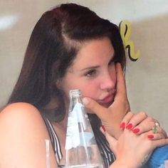 a woman with her hand on her face next to a water bottle