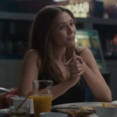 a woman sitting at a table with food and drinks