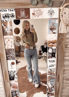 a woman standing in front of a mirror wearing a cowboy hat and holding a camera