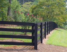 a black fence in the middle of a grassy field