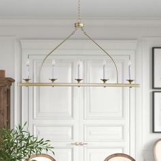 a chandelier hanging over a dining room table with chairs and a potted plant