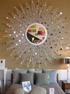 a large sunburst mirror mounted on the wall above a bed with pillows and lamps