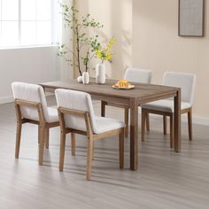 a dining room table with four chairs and a plate of fruit on the wooden table