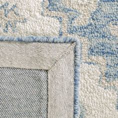 the corner of an area rug with blue and white designs on it's edges