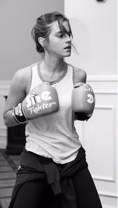 a black and white photo of a woman wearing boxing gloves with one hand on her hip