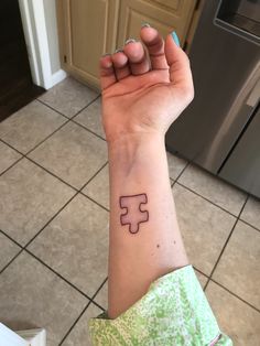 a woman's arm with a piece of puzzle tattooed on the middle of it