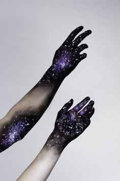 two hands reaching up into the sky with stars painted on their palms and arms, both holding each other