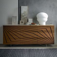 a wooden cabinet with an abstract design on the front and side, next to a white vase