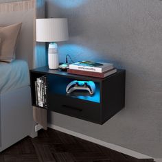 a nightstand with a video game controller on it next to a lamp and bookcase