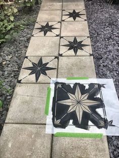 some black and white stars are painted on the ground next to a garden path that is lined with plants