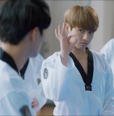 the boy is wearing a karate uniform and holding his hand up in front of him