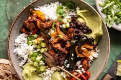 a bowl filled with rice, beans, and other food on top of a table